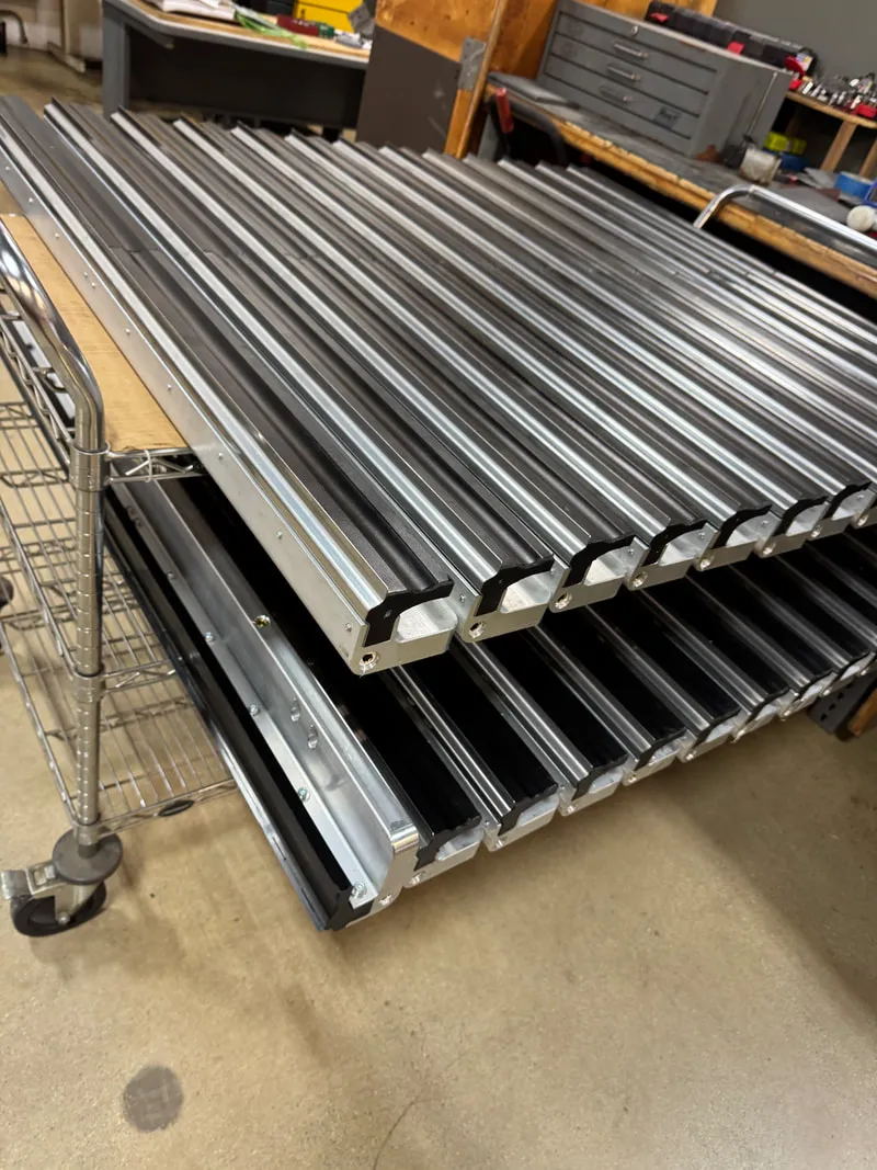 Rows of long metal components stacked on a wheeled rack